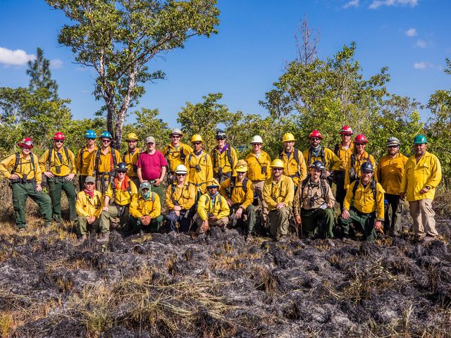 Nearly 30 fire practitioners stand together and pose for a group photo in Belize, following a prescribed fire training exercise.