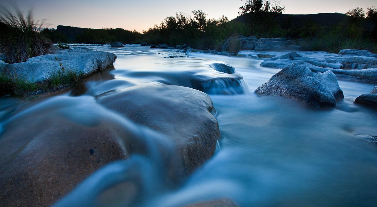 Water cascading over large rocks in a river.