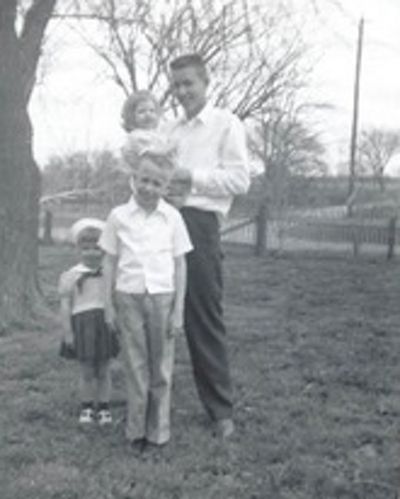 Black-and-white photo of four children posing on a farm. 