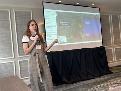 TNC's Denise Perez stands next to a large screen and makes a presentation.