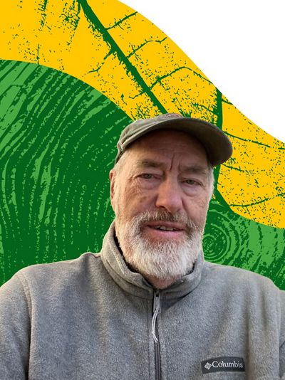 An older white man with a white beard and a baseball hat smiles in front of a digitally edited background that has green and yellow curved sections.