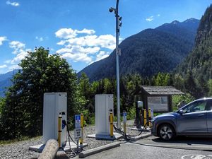 Un vehículo eléctrico está en una estación de carga en un paisaje montañoso de Columbia Británica.