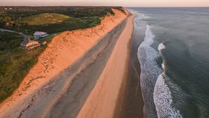 A high sand bluff is seen from above. Two houses sit within a few hundred feet from the edge of the bluff