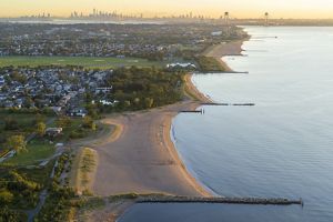 In the foreground several housing developments are seen along a beach, in the distance, the NYC skyline and bridges are visible