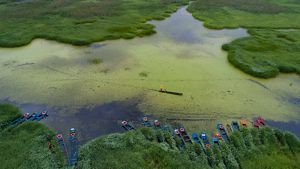 A fisher pushes his canoe through a river in Yunnan.