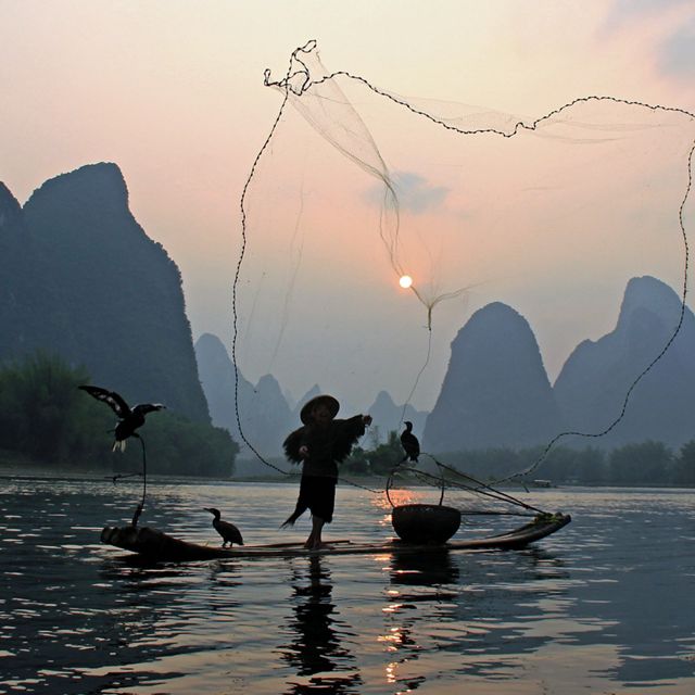 on the Li River during a misty, cloudy evening in Guangxi, China.