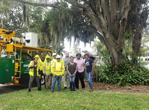 A group of people pose together under a tree.