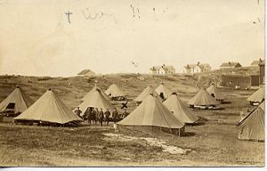 Historical photo of Army base Fort Terry showing 12 tents in foreground and buildings in the background. 