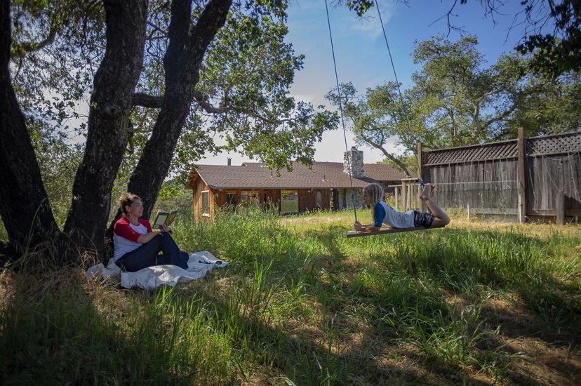 Scientist Heather Tallis sits under a tree at her house in California facing her son on a swing. 