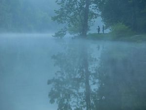 anglers fish on a misty lake