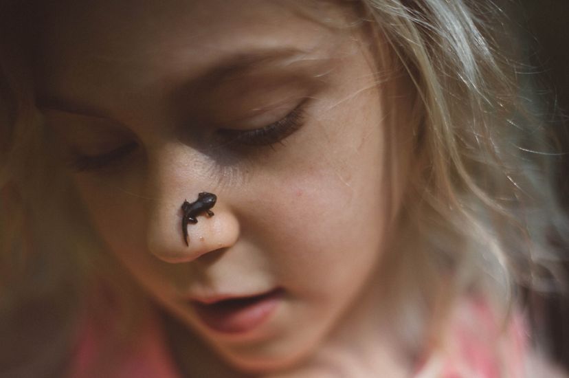 Closeup of a girl with a tadpole on her nose.