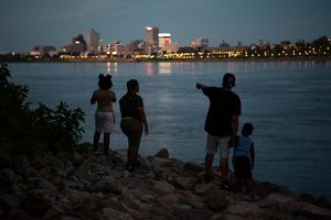 A family stands by the river at twilight, looking across the river at the Memphis skyline.