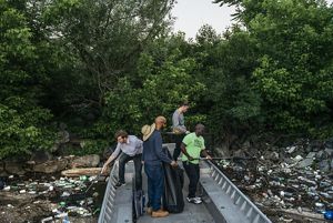 Four men scoop trash from the river's surface with nets.