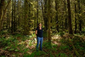 Kaylee Kenison standing in a forest of thick trees in Washington.