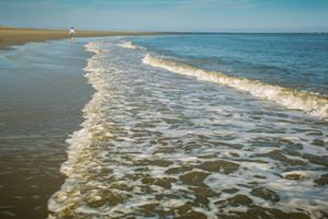 The sandy beach of the Atlantic with small calm waves lapping the shore.