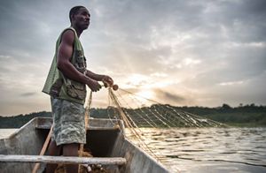 Man pulls a fishing net from a small boat 