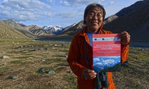 Portrait of Gala Davaa holding up a report about Western Mongolia.