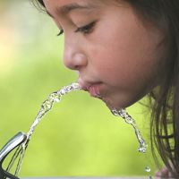 Girl drinking water from a fountain.