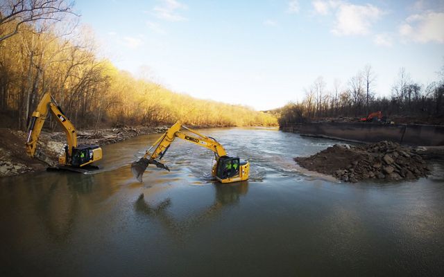 Yellow diggers sit mid-stream and remove debris from the river.