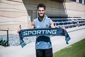 Sporting Kansas City's Graham Zusi holds a Sporting Sustainability match scarf. 