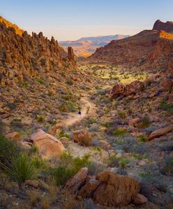 A person walks along a trail in a rocky valley.