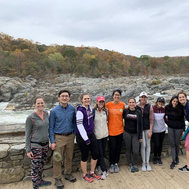 A group of people stand together on a platform overlooking a river rushing through a rocky landscape.