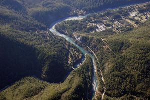 Aerial view of a river meandering through forested mountains with a small town alongside the river.