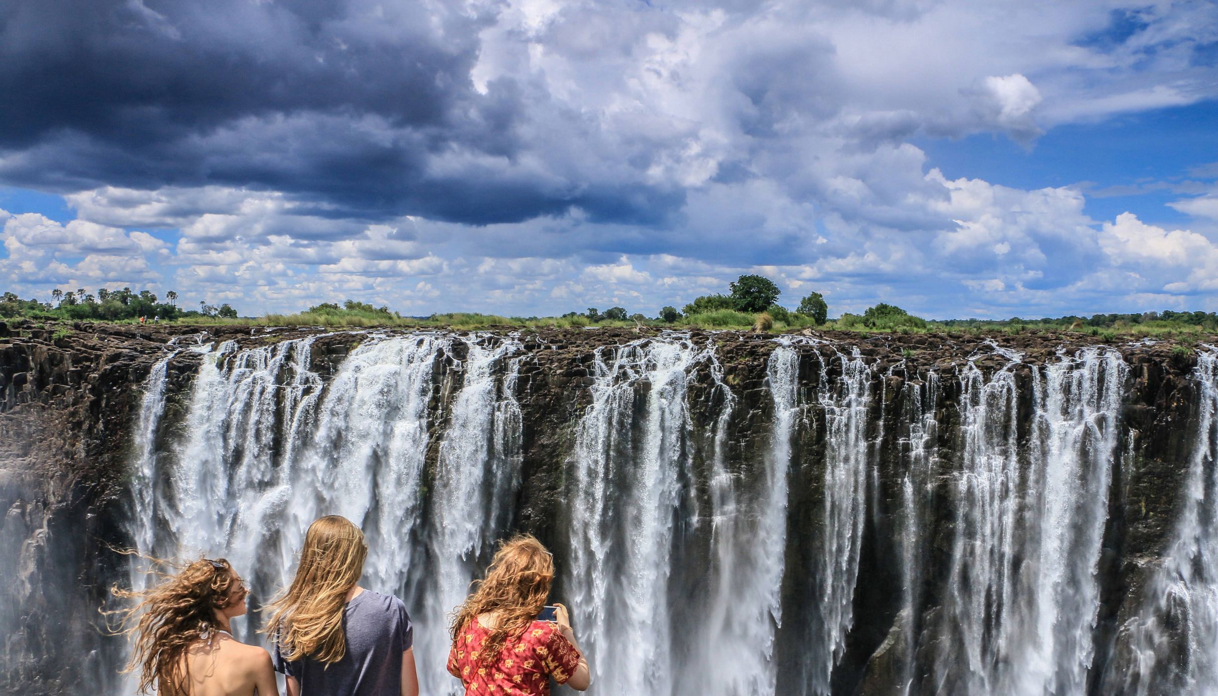 Tres personas frente a las cataratas Victoria en el sur de África