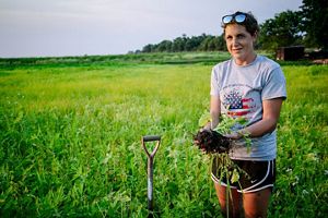 Farmer Allison Grimm holds up crop roots to show good soil health.