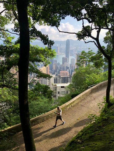 A man takes a walk through a green area at Victoria Peak overlooking Hong Kong.