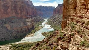 A river flows through a narrow, orange canyon.