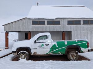 A truck is parked in snow with a cabin behind it.