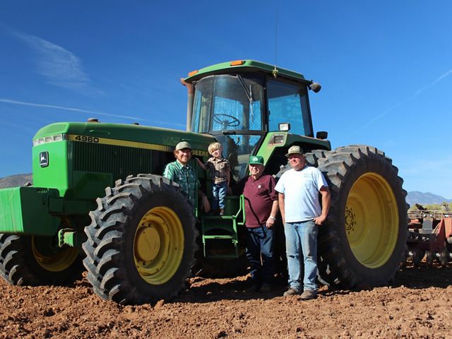four people stand in front of a tractor 
