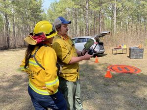 A woman looks over a man's shoulder at the handheld display he holds during a demonstration of fire drone technology.