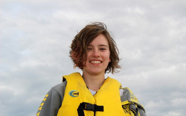 A smiling woman wearing a yellow life jacket.