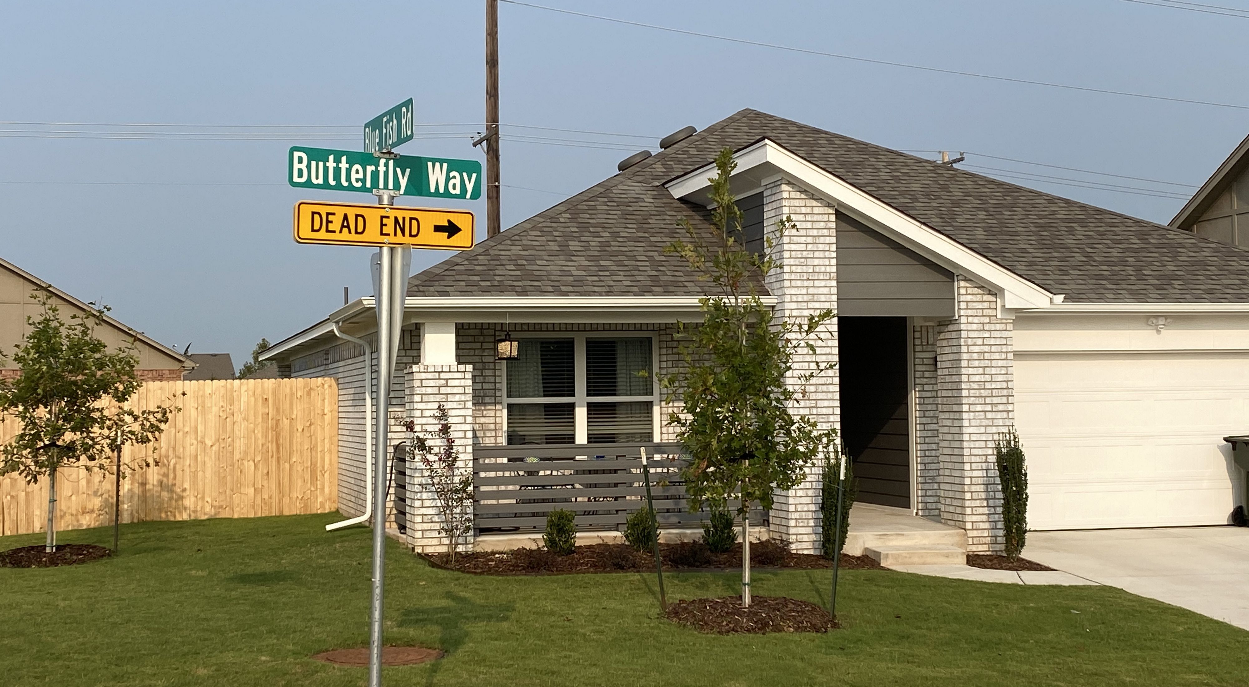 A street sign named "Butterfly Way" leading towards pollinator gardens in a housing addition.