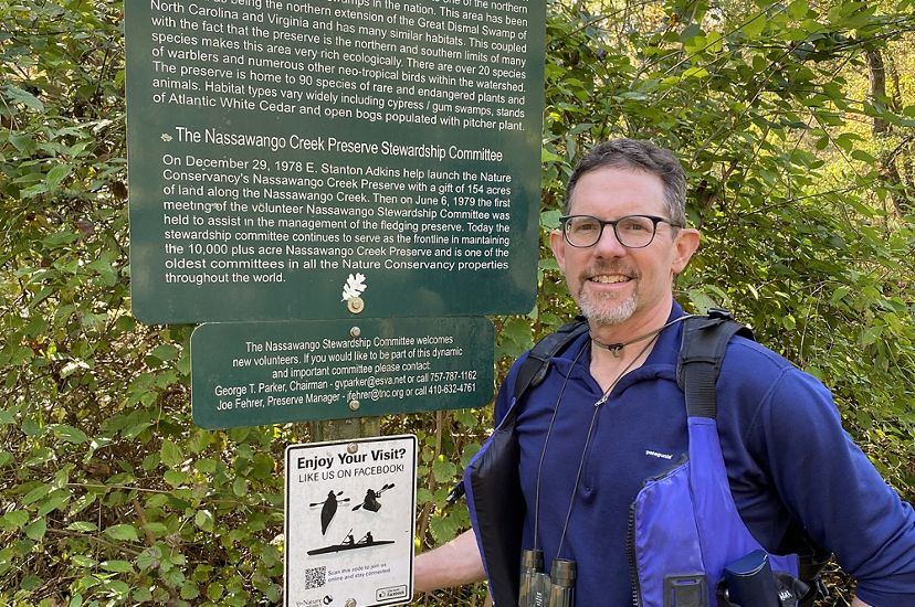 Steve Volkers stands next to a green information sign at Nassawango Creek Preserve.
