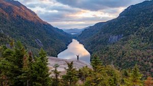 View looking up the length of a dramatic valley with a figure standing on a ledge in the medium distance.