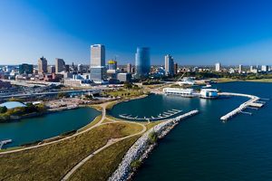 Aerial image of Milwaukee skyline on a blue sky day with Discovery World and Lakeshore State Park in the foreground.