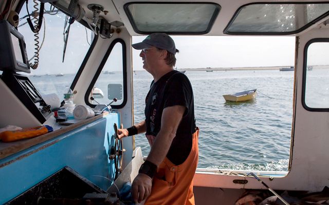 A fisherman on a New England commercial fishing vessel steers the boat.