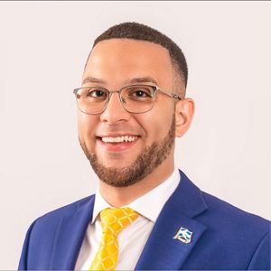 Headshot of Jonathan Guzman in a blue suit jacket and yellow tie.
