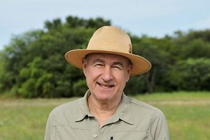 Hombre con sombrero sonriendo frente a la camara.