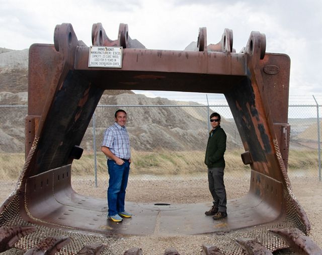 Two men standing under a bell.