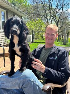 Candid photo of Jeff Walk, Leveraging Our Lands Director for TNC's Midwest Division, with his small black dog on his lap.