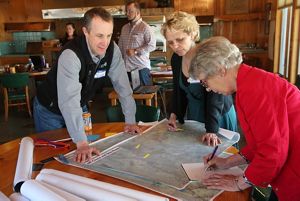 Bill Patterson reviews maps on a table with two women.