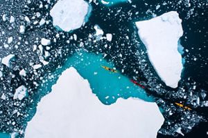 Kayakers paddling through ice.
