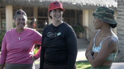 Three people stand together outside and enjoy a laugh.
