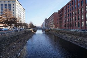 North Canal runs through a section of downtown Lawrence with large buildings on either side.