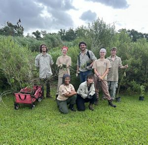 A group of seven young people stand in front of a field.