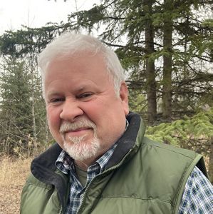 Man in vest outdoors smiling.